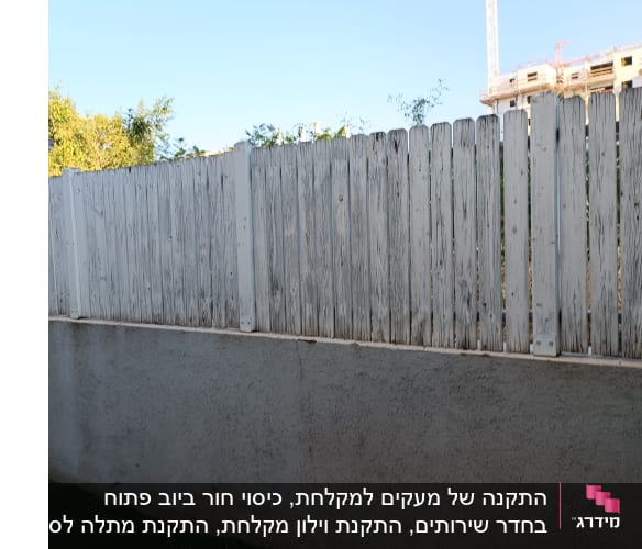 גדר עץ לבנה על קיר בטון